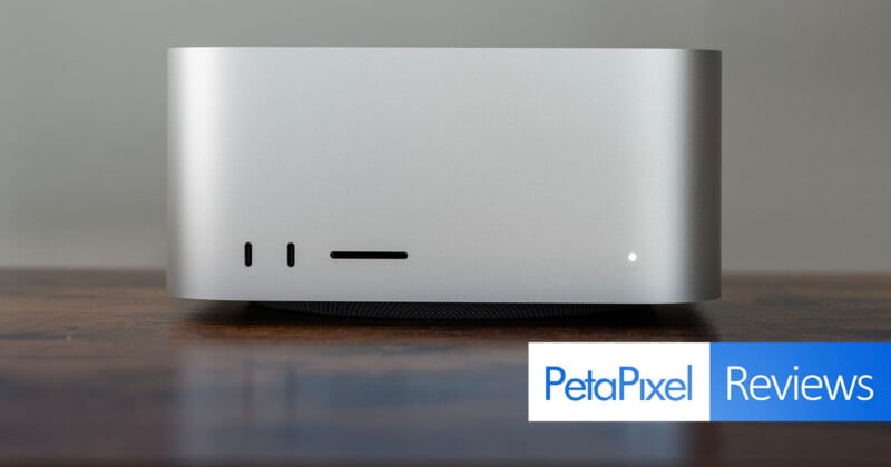 A sleek, silver desktop computer sits on a wooden surface against a plain background. The lower right corner has a "PetaPixel Reviews" label.