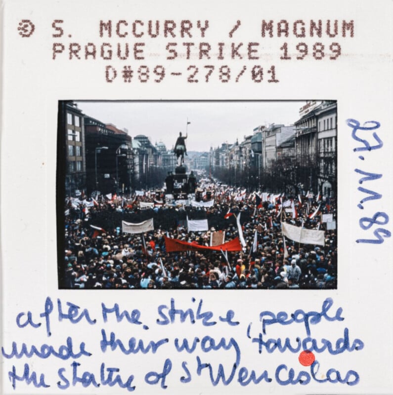 A large crowd gathers in Prague's Wenceslas Square during the 1989 strike, viewed from a distance. Numerous flags and banners are visible. The statue of St. Wenceslas stands prominently in the background. Handwritten text annotates the event details.
