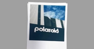 A Polaroid photo of a building with the word "polaroid" on it. The building features a modern design with vertical lines and a mix of white and dark colors. The sky is partly cloudy in the background.