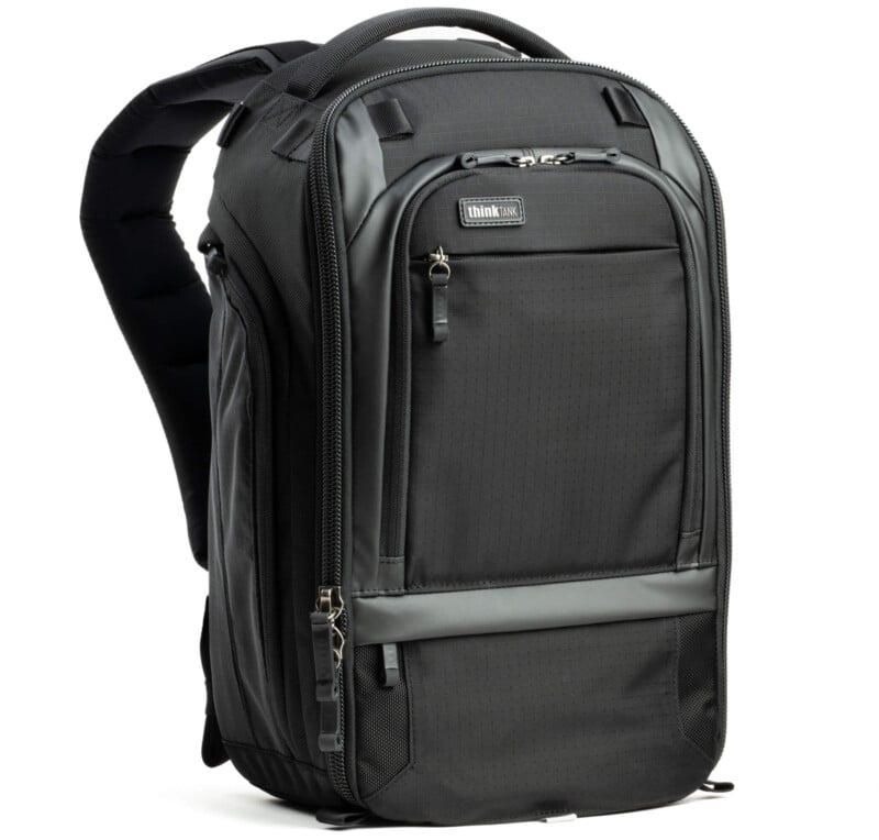 A black, structured backpack with multiple compartments and zippers. It has padded shoulder straps and a small logo on the upper front. The sleek design features a combination of smooth and textured fabric.