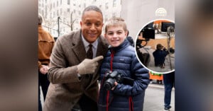 A man in a brown coat and gloves poses with a smiling boy holding a camera. They're outdoors with cameras and equipment in the background. An inset shows the boy photographing the scene.