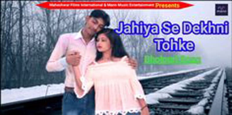 A man and woman stand close together beside railway tracks in a snowy landscape. The image includes the text "Jahiya Se Dekhni Tohke.