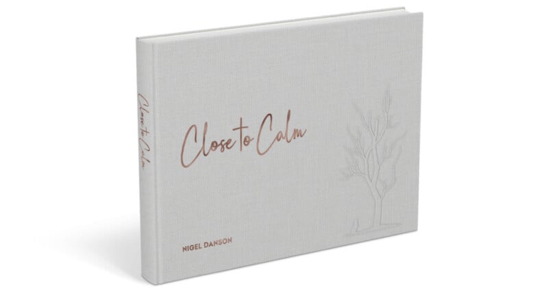 A hardcover book titled "Close to Calm" by Nigel Danson. It has a minimalist design with light gray cover and subtle line art of a tree. The title is written in elegant script.