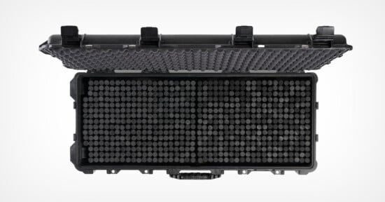 A black hard-shell protective case with an open lid, revealing a grid of cylindrical compartments inside. The lid has egg crate foam padding for cushioning contents.