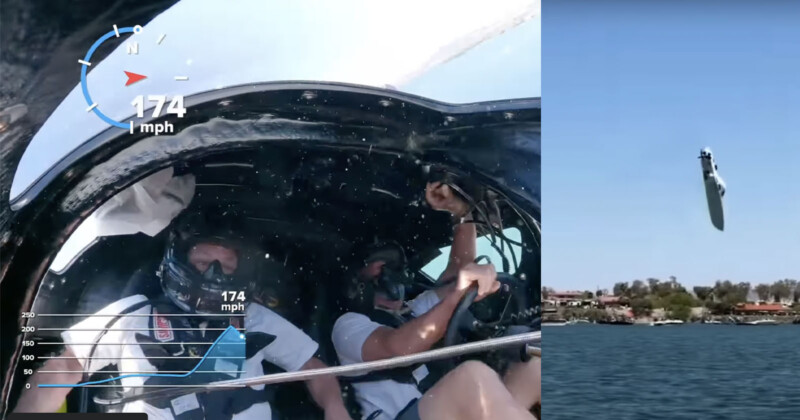 Two people in helmets sit inside a speedboat going 174 mph, as seen on a speedometer overlay. The boat is airborne, tilted upwards over water, with lakeside houses visible in the background.