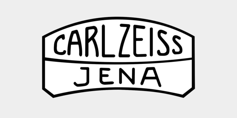 Black and white logo with the words “CARL ZEISS” in large letters above “JENA” in smaller letters, all enclosed in a geometric, arch-shaped border.