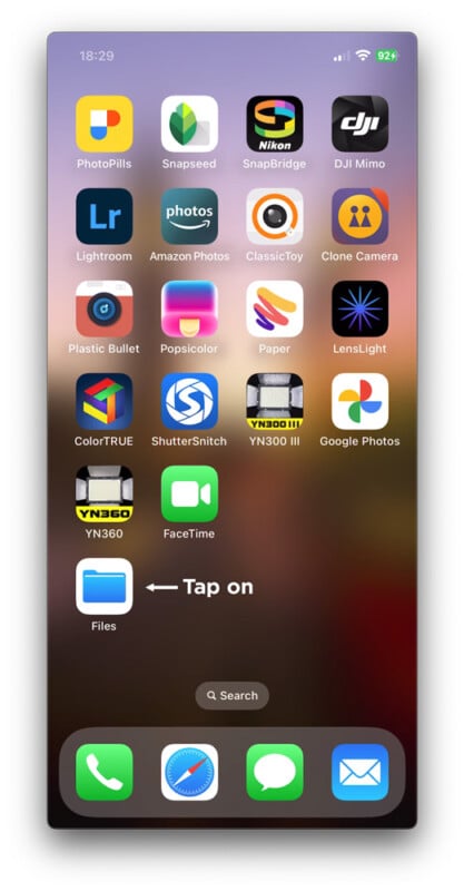 Screenshot of an iPhone home screen showing various app icons, with a white arrow and text pointing to the Files app icon at the bottom left, saying "Tap on".