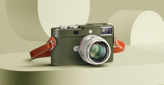 A green and silver digital camera with a brown leather strap is displayed on a pale green surface, with a soft-focus geometric background in similar tones.