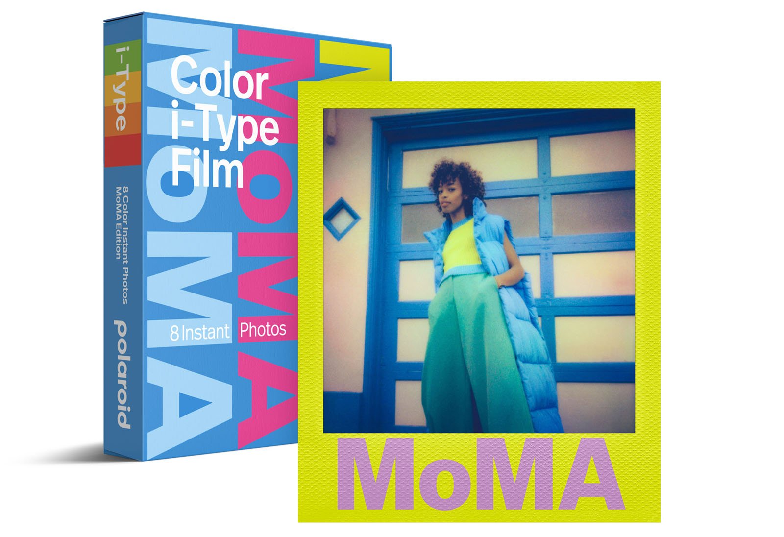 A box of Polaroid Color i-Type film with MoMA branding stands next to an instant photo of a person in a blue coat and green pants posing in front of a blue door. The photo frame is yellow and says “MoMA” at the bottom.
