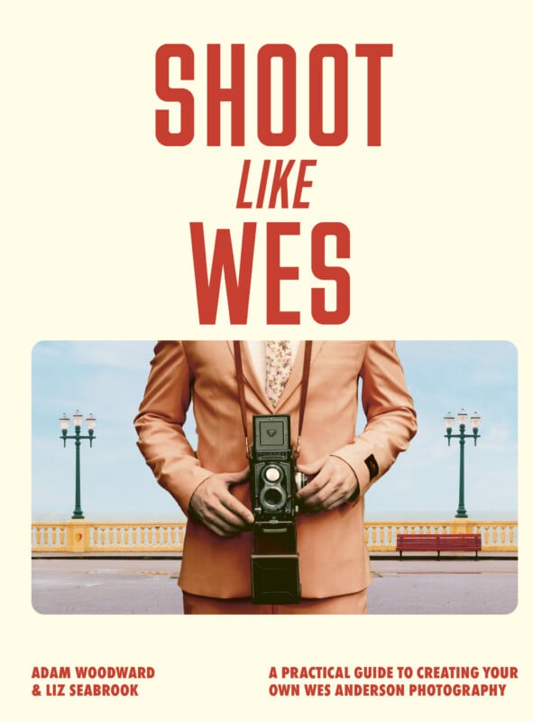 Book cover for "Shoot Like Wes" featuring a person in a peach suit holding a vintage camera, standing in front of a pastel promenade with ornate street lamps.