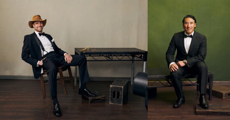 Two men in tuxedos sit on either side of a table in a studio. One wears a cowboy hat and leans back in a chair, while the other sits upright on a bench. The background is divided between beige and green.