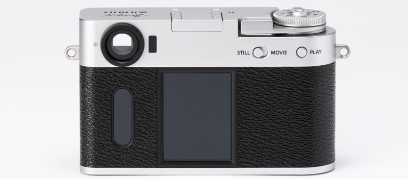 A silver and black Fujifilm digital camera, viewed from the back, showing a large screen, control buttons, mode dial, and textured grip.