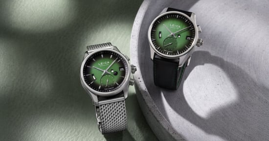 Two luxury Leica watches with green dials; one has a metal mesh band and the other a black leather strap. Both are placed on a green and gray textured surface with soft lighting and shadows.
