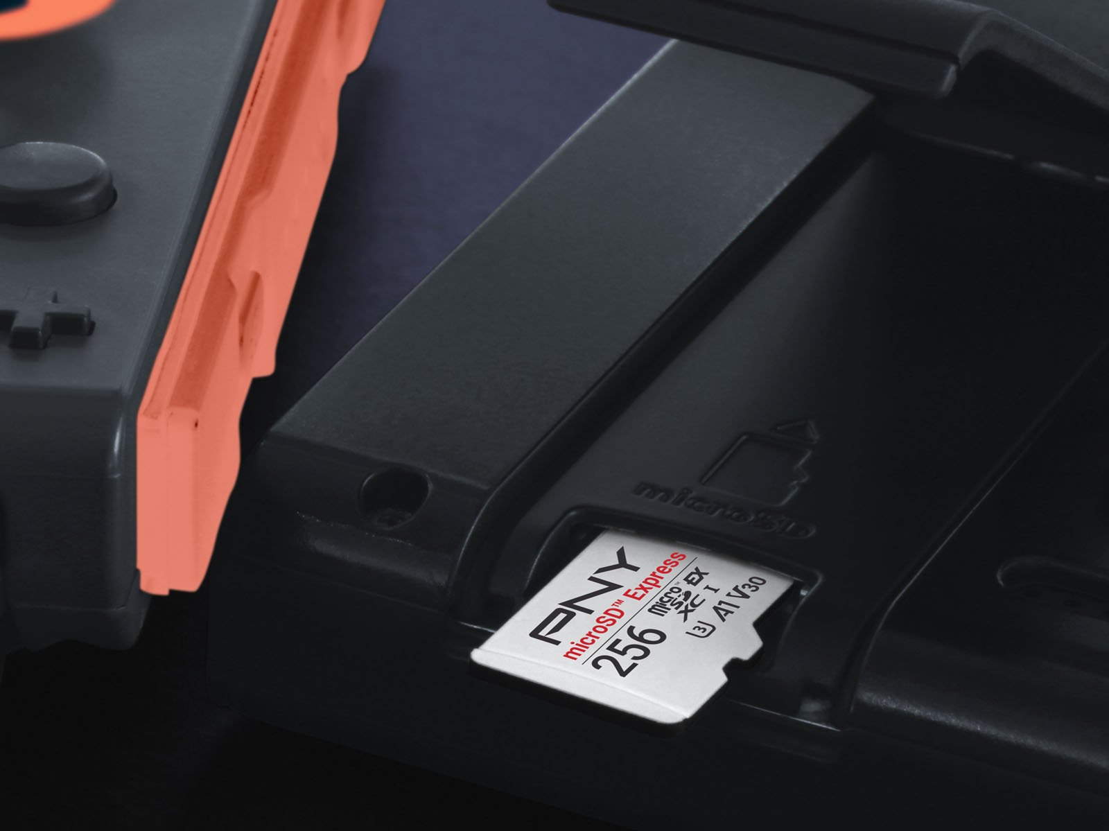 A close-up of a PNY 256GB microSD card being inserted into a Nintendo Switch console, with part of the red Joy-Con controller visible on the left.