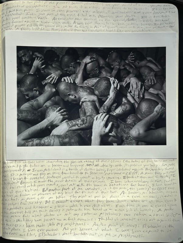 A black-and-white photo of a group of tattooed men closely packed together, many with shaved heads and hands over their heads. The image is framed on a page filled with handwritten text in the margins.