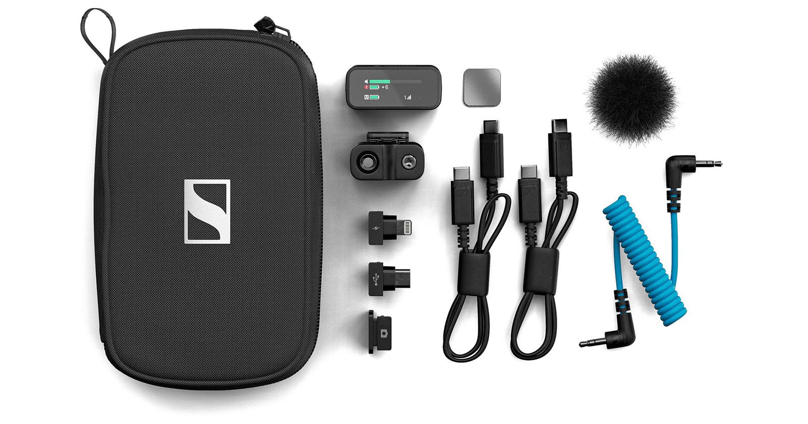 Flat lay of an audio recording kit with a black zippered carrying case, small audio receiver, adapters, two cables, lightning and USB-C connectors, a fuzzy windscreen, and a blue coiled audio cable arranged neatly.
