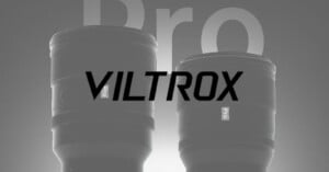 Two camera lenses labeled "Pro" are shown side by side with the word "VILTROX" prominently overlaid across the image. The background is gray with large, faded letters reading "Pro.