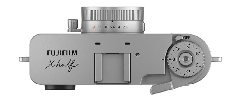 Top view of a silver Fujifilm X half camera showing the shutter speed dial, aperture ring, and on/off switch, with "Fujifilm X half" branding clearly visible.