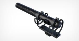 A black shotgun-style condenser microphone with shock mount and adjustable settings, designed for professional audio recording, is shown on a plain white background.