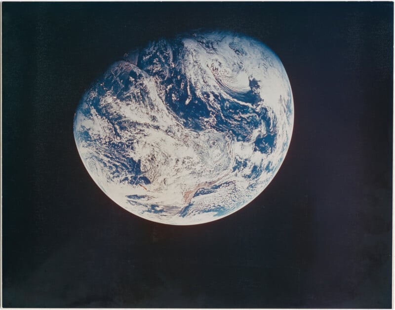 A view of planet Earth from space, showing swirling white clouds, blue oceans, and continents against the blackness of space.