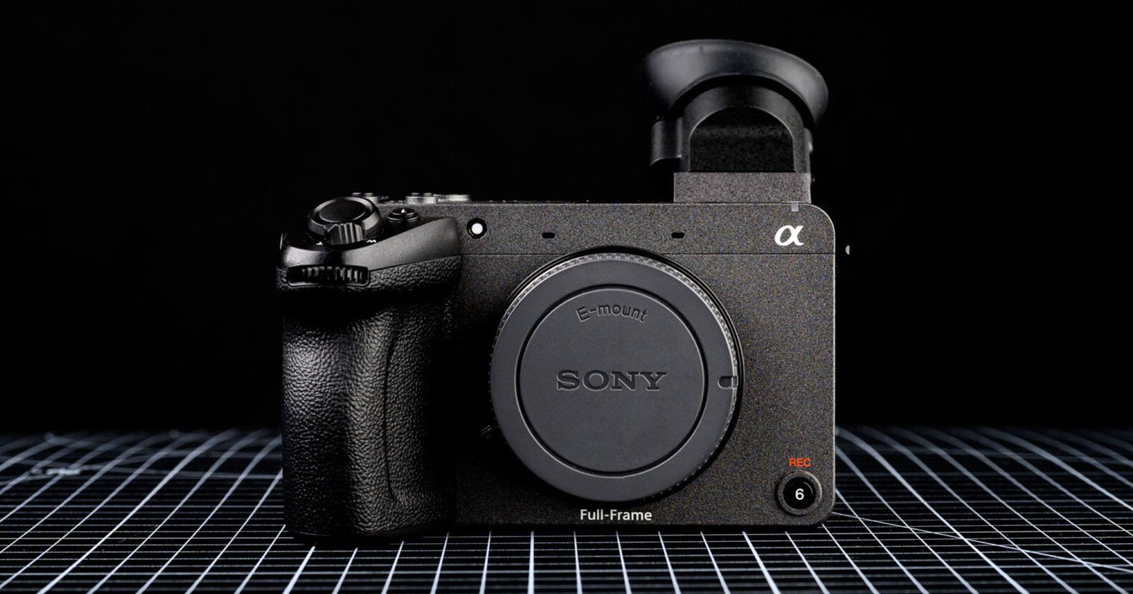A Sony full-frame mirrorless camera body with an E-mount, displayed on a grid-patterned surface against a black background.