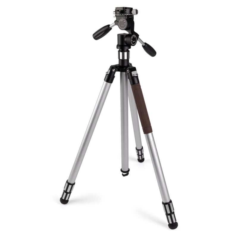 A silver and black camera tripod stands on three adjustable legs with rubber feet, featuring a pan-and-tilt head and two control handles.