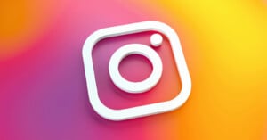 A white Instagram logo icon is displayed on a vibrant, gradient background blending pink, orange, and yellow colors.