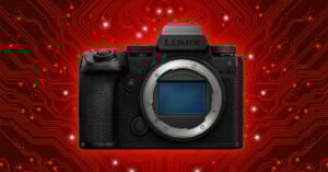 A Lumix digital camera body is centered against a glowing red circuit board background with white lights highlighting various circuit paths.