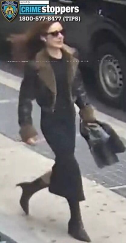A person with long hair wearing sunglasses, a dark jacket with fur trim, a black skirt, and heeled boots is walking on a city sidewalk carrying a jacket. Crime Stoppers and tip line information is visible at the top.