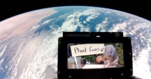 A view of Earth from space with a CrunchLabs frame in the foreground displaying an image of a squirrel next to a sign that says "Phat Gus.