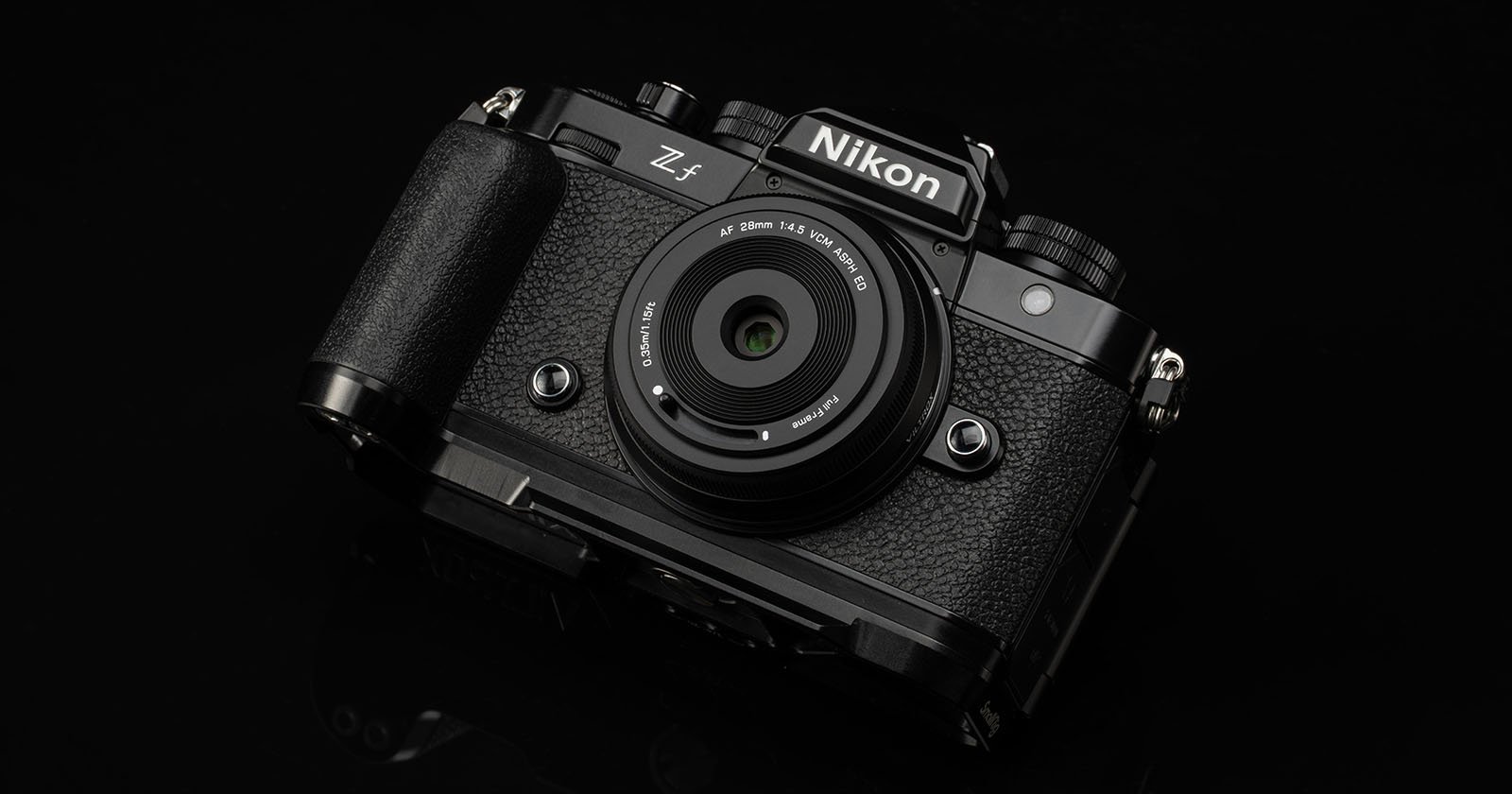 A black Nikon Z f mirrorless digital camera with a textured grip and attached lens is displayed on a dark background.