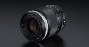 A close-up view of a Voigtländer camera lens with "PORTRAIT HELIAR 75mm F1.8" and various aperture settings visible, set against a dark, reflective background.