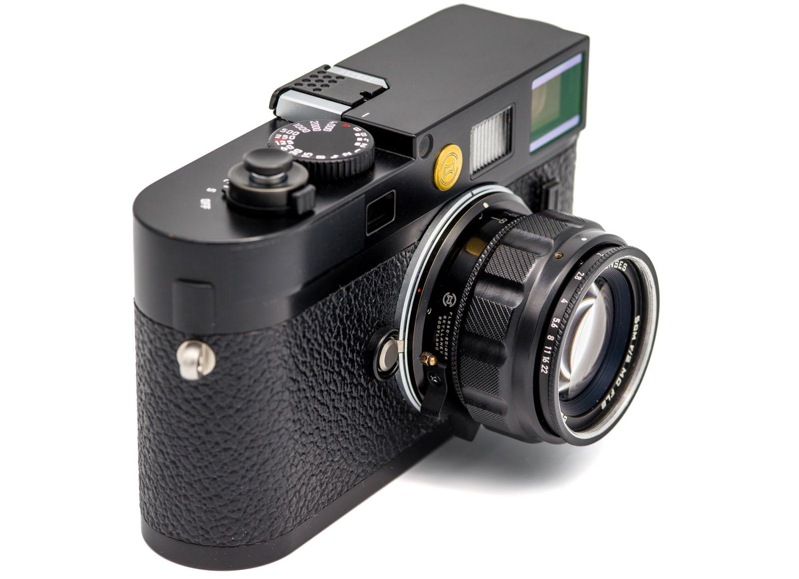 A black, vintage-style digital rangefinder camera with a textured grip and attached lens, shown at an angle on a white background.