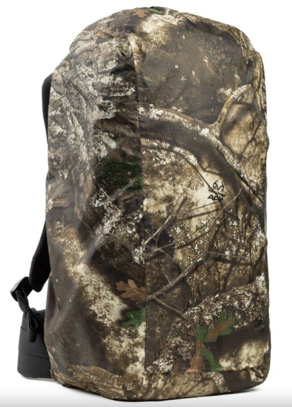 A camouflage-patterned backpack cover featuring realistic images of tree bark, branches, and leaves, designed for blending in with forest environments. The cover fits snugly over a backpack.