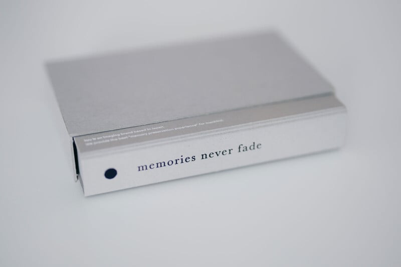 Kyu Camera Unveiled: Revolutionizing the Art of Memory Capture 12 A closed, gray hardcover book lying on a white surface. The spine displays the phrase 'memories never fade' in lowercase black letters. The book has a minimalist design.