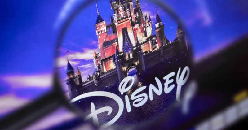 A magnifying glass focuses on the Disney logo in front of a castle, with a purple and blue background, highlighting the castle's details and the stylized "Disney" text.