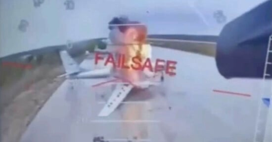 A plane on a runway is engulfed in flames and smoke, viewed through a cockpit display with the red warning text "FAILSAFE" superimposed over the scene.