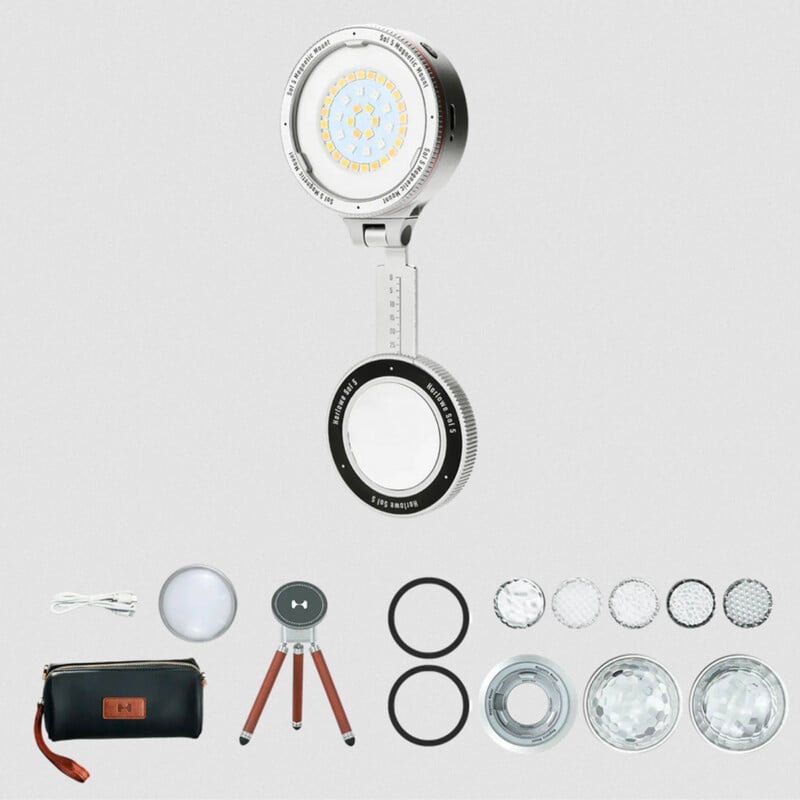A portable LED photography light kit with a round light, adjustable stand, carrying case, tripod, charging cable, multiple lens filters, and rings arranged on a light background.