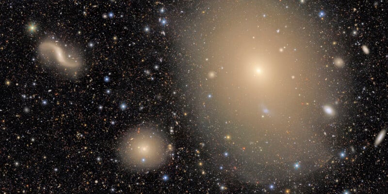 A dense field of distant stars and galaxies, with several large, bright, fuzzy elliptical galaxies glowing against a dark sky filled with smaller, colorful points of light.