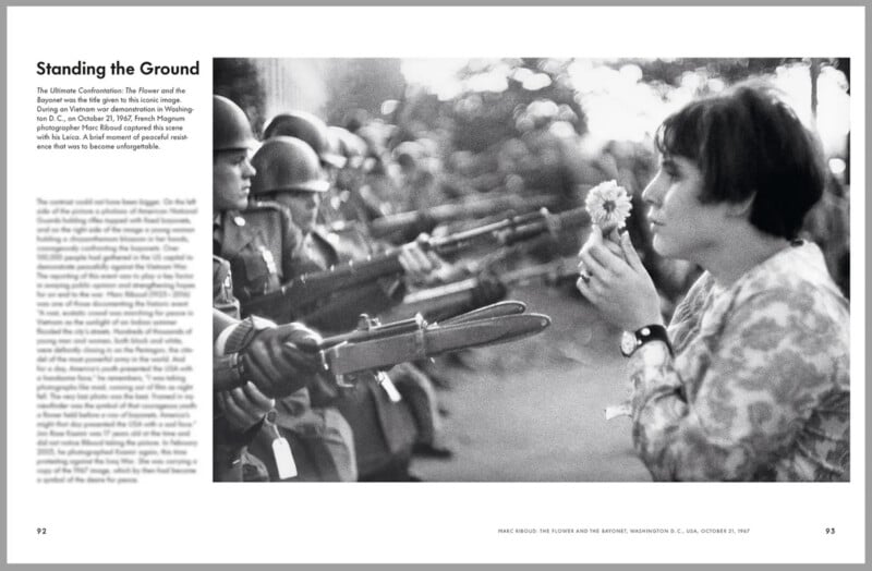 A woman stands facing a line of armed soldiers with rifles and bayonets, holding a flower close to her face, calmly smelling it amidst the tense standoff. The left side contains text under the heading "Standing the Ground.