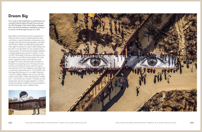A large black-and-white photo of a child’s eyes is displayed across the U.S.-Mexico border fence, surrounded by people on both sides, highlighting unity and division at an outdoor art installation.