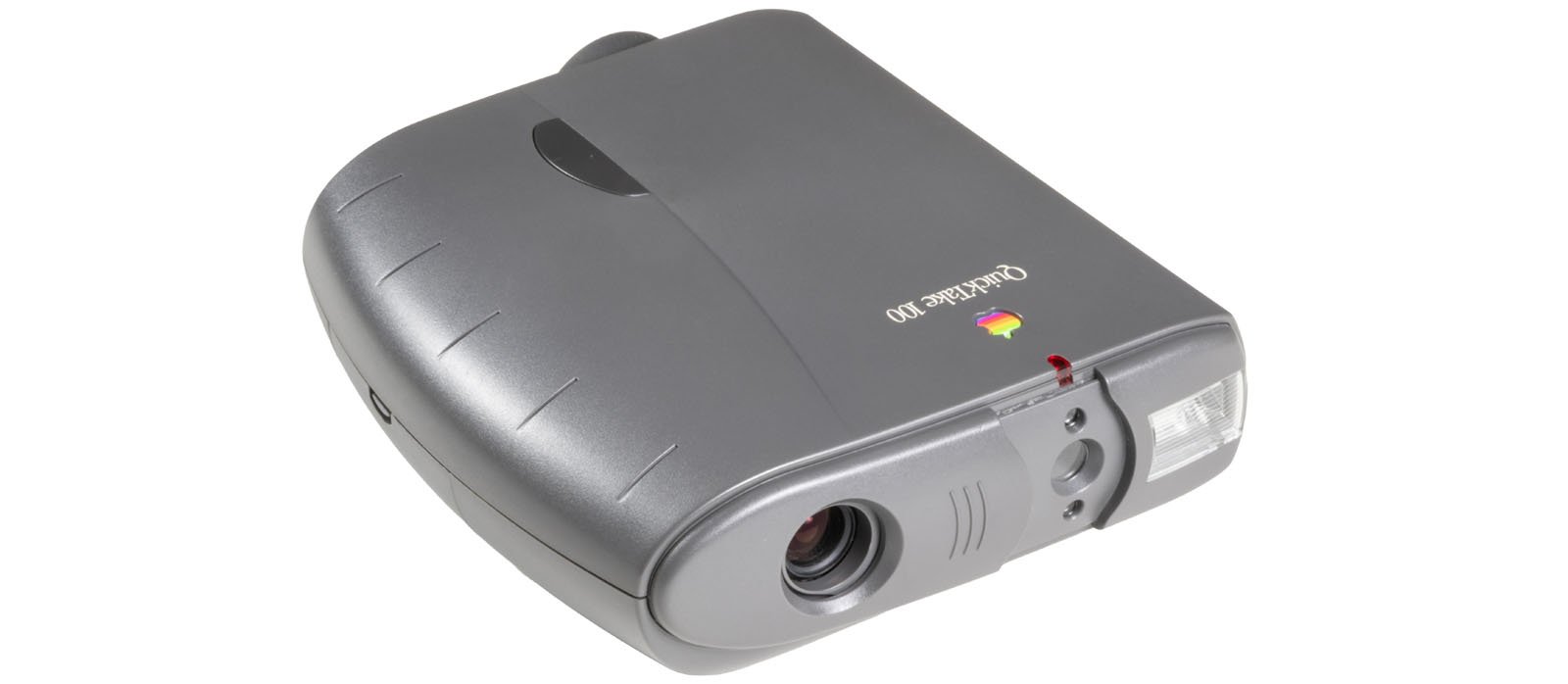 A vintage Apple QuickTake 100 digital camera in gray, shown from a front angle, featuring a prominent lens, viewfinder, and curved edges.