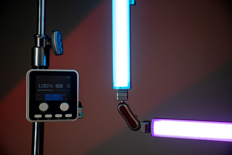 A close-up of an LED light setup with a control panel displaying settings, and two segmented light bars glowing in blue and purple against a dark, blurred background.