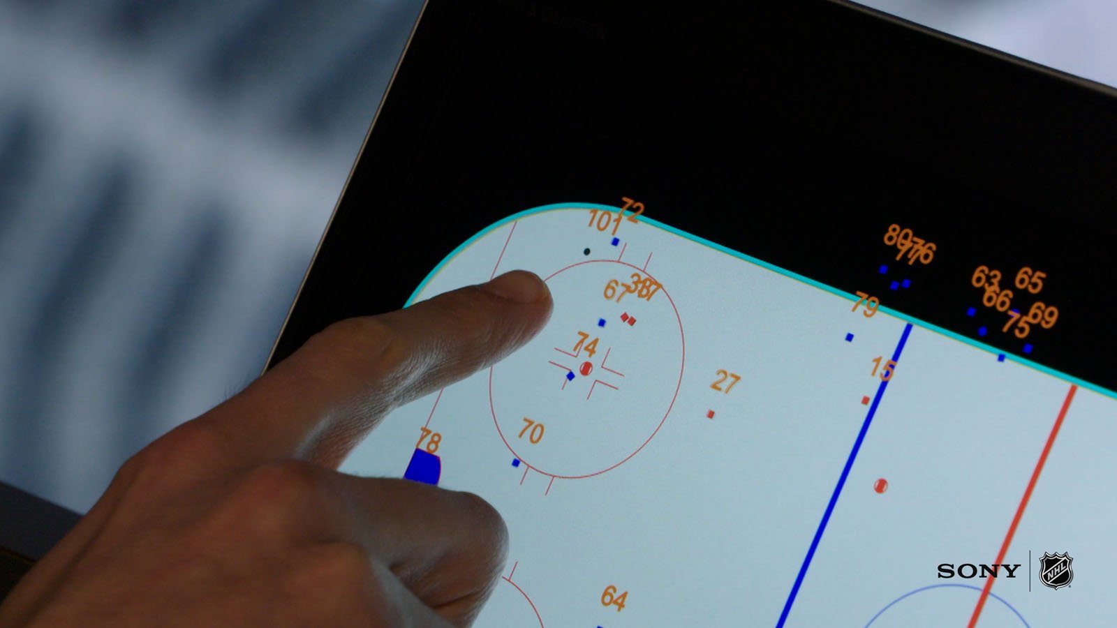 A hand points to player statistics on a digital hockey rink diagram displayed on a screen, with the SONY and NHL logos in the bottom right corner.