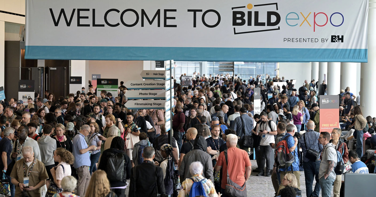 A large crowd gathers under a "Welcome to BILD expo" banner at a convention center, with directional signs for various stages and exhibitors visible.