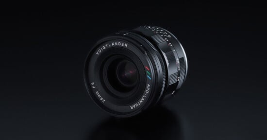 A Voigtländer APO-LANTHAR 35mm f/2 camera lens is displayed on a glossy black surface, showing its detailed engravings and multicolored logo markings near the front element.