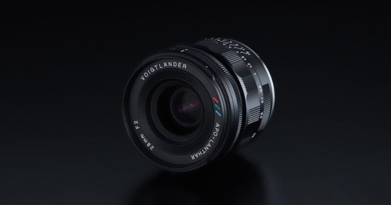 A Voigtländer APO-LANTHAR 35mm f/2 camera lens is displayed on a glossy black surface, showing its detailed engravings and multicolored logo markings near the front element.