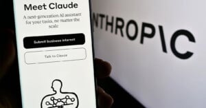 A smartphone screen displays the introduction to Claude, an AI assistant by Anthropic, with options to submit business interest or talk to Claude. The word "Anthropic" is blurred in the background.