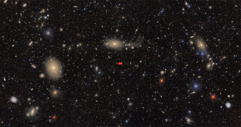 A field of countless distant galaxies and stars fills the dark sky, with a small red rectangle marking a specific spot near the center of the image.