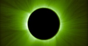 A black circle at the center is surrounded by a vivid green corona, resembling a solar eclipse with glowing, wispy light rays radiating outward on a dark background.